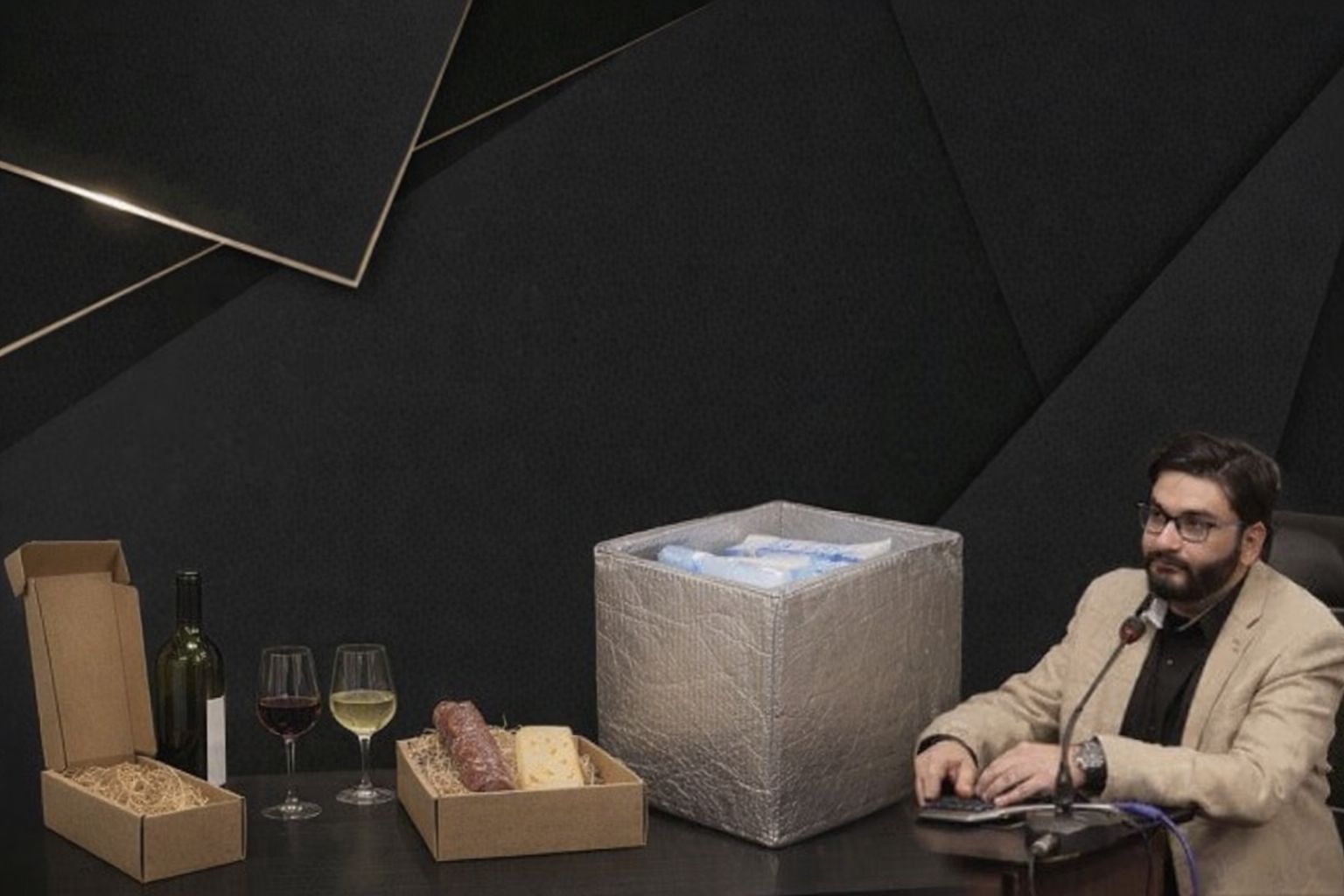 Mann am Schreibtisch mit Wein, Feinkost und einer Kühlbox, bereit für den Versand.