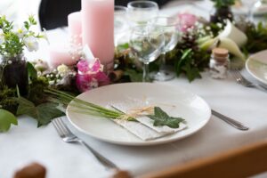 Sommerlich gedeckter Tisch mit Leinenserviette, Wildkräutern und Blumen